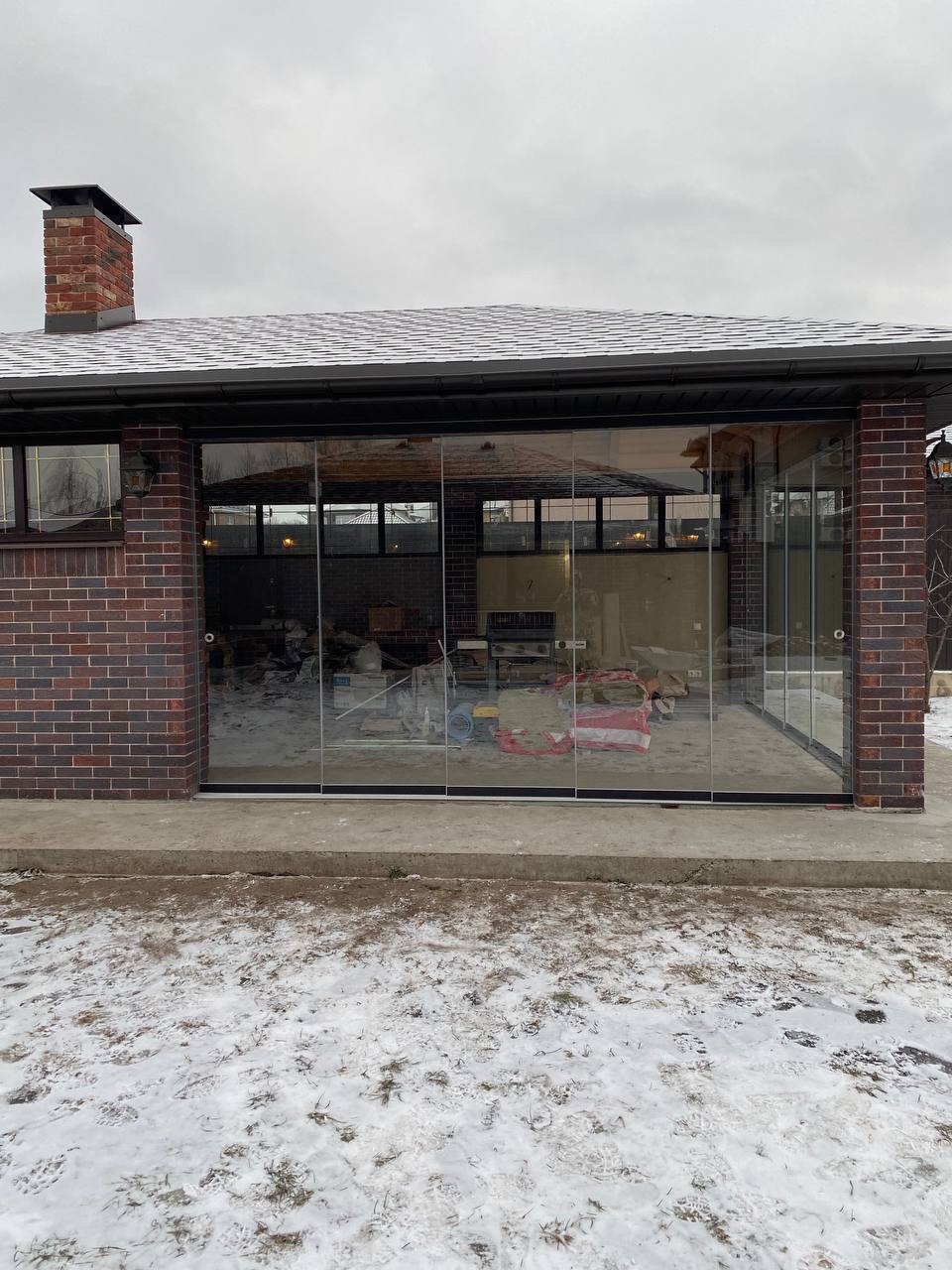 Brick pavilion with outdoor kitchen and frameless glass enclosure in Littleton, Colorado